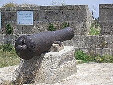 Un canon monté sur le mur de la ville d'Akko près du panneau commémoratif en l'honneur de Chaim Farhi