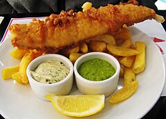 Fried fish and chips with lemon, ketchup, tartar sauce and mushy peas, as served in London Fish, chips and mushy peas.jpg