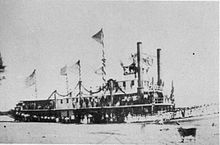 一張帶有2支煙囪的蒸汽船停靠於河岸邊黑白照片。