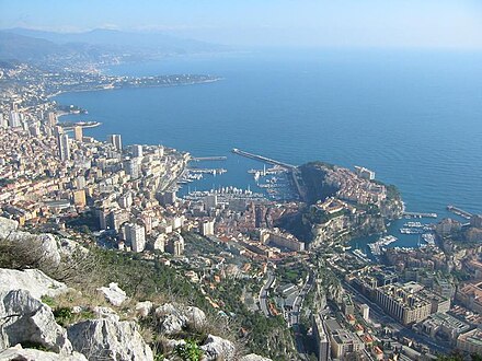 In the centre is La Condamine. At the right with the smaller harbour is Fontvieille, with The Rock (the old town, fortress, and Palace) jutting out between the two harbours. At the left are the high-rise buildings of La Rousse/Saint Roman.