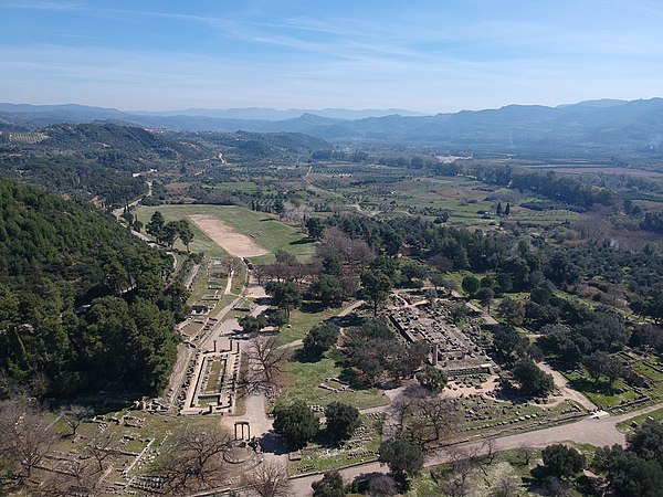 The archaeological site showing the stadium, the temple of Hera, the temple of Zeus. The line of trees, upper right, border a road to the north of the