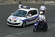 National Police officers using various forms of transportation, namely a police car, a police motorcycle, and foot patrol Police preparant l'arrivee d'une manifestation.JPG
