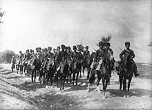 Jízdní oddíl kozáků pózující fotografovi na polní cestě.