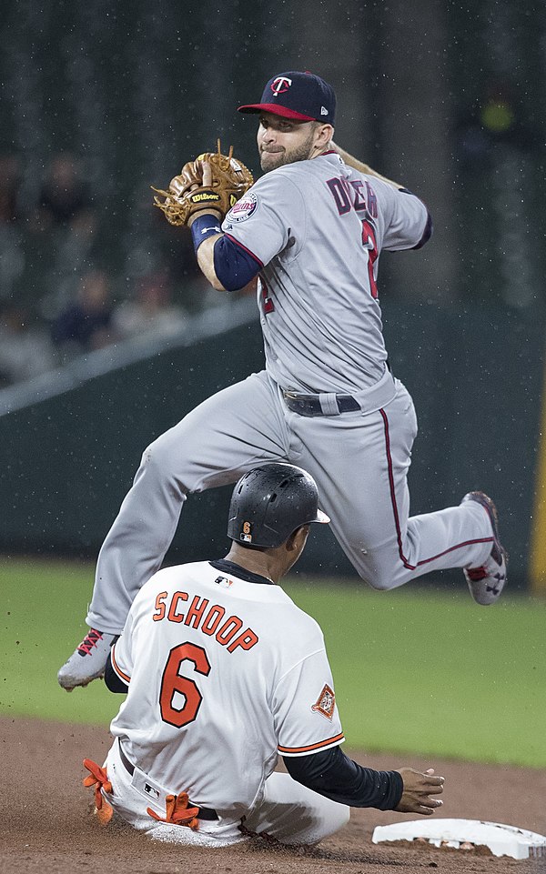 Brian Dozier of the Minnesota Twins leaps over a sliding Jonathan Schoop of the Baltimore Orioles attempting to turn a double play.