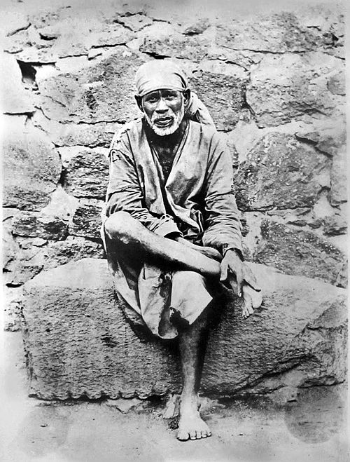 Shri Saibaba sitting on a stone.