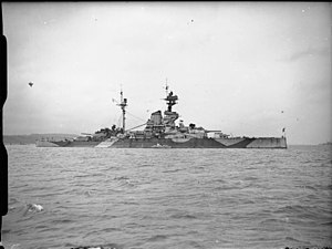 a stationary warship in harbour painted in camouflage