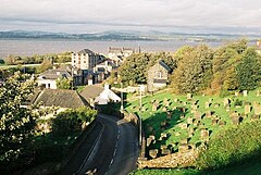 A view of Bo'ness from a hill with a cemetery on the right, houses on the left and the Firth of Forth and Fife in the distance
