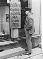 A man reads a sign advertising "Attention, Unemployed, Haircut 40 pfennigs, Shave 15 pfennigs", 1927.