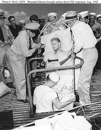 A Marine Raider, injured during the Makin operation, is lifted through a hatch on USS Argonaut to be taken ashore at Pearl Harbor, 26 August 1942.