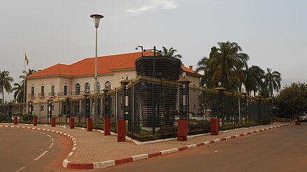 The Bissau-Guinean  Presidential Palace, with its Portuguese colonial architecture, is a building that has a library, a small theater and was formerly the palace of the colonial governor of Portuguese-Guinea, seen from the PAIGC-building (formerly the seat of the local commercial association Associação Comercial, Industrial e Agrícola de Bissau), located at the Praça dos Heróis Nacionais square (formerly Praça do Império square), in downtown Bissau.