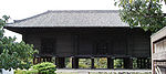 Sombre bâtiment en bois avec plancher surélevé sur des poteaux.