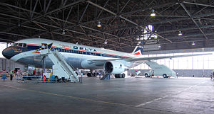 Side view of a parked Delta Air Lines twin-engine jet in hangar, with stairs mounted next to the aircraft's forward door