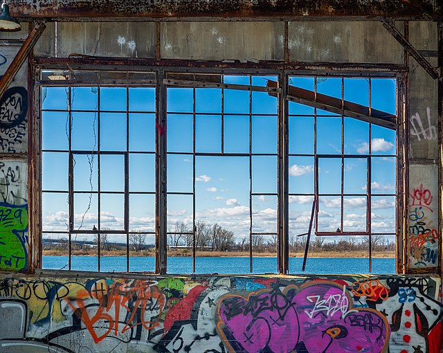 La structure restante d'une fenêtre qui n'a plus aucune vitre se découpe sur le paysage comme le ferait un vitrail.