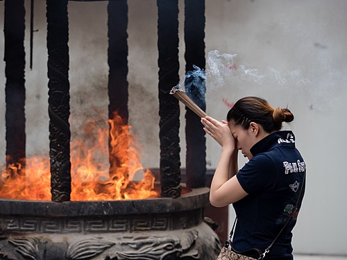 Woman burning incense at Jade Buddha Temple in Shanghai