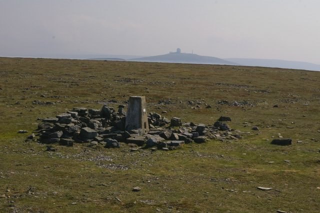 The summit of Cross Fell with Great Dun Fell and its radar station in the background. The object in the centre foreground is a triangulation point
