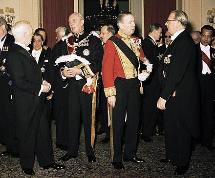 Diplomatic reception in West Germany (1961); the Danish ambassador wears a red diplomatic uniform, the British ambassador a dark one.
