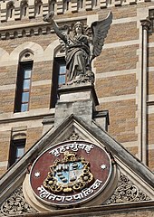 Winged allegorical figure representing the 'urbs prima in Indis' and the coat of arms of MCGM below Gable of BMC Building.jpg
