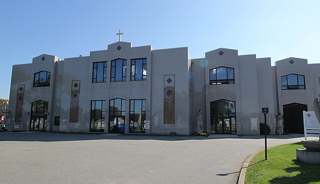 Two-story white building topped with a Christian cross