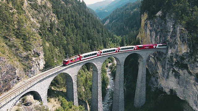 The Glacier Express (here on the Landwasser Viaduct) is the longest distance train in Switzerland. It runs from Zermatt to St. Moritz, on both MGB and
