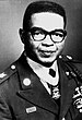 A black and white image showing the head and torso of Joel in his military dress uniform with ribbons. His Medal of Honor is vsible around his neck.