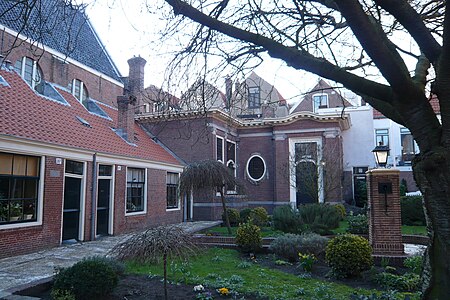 The Lutherse Hofje is situated on the north side of the church, with several rooms (left) attached to the church itself. In the back of the small houses is the Regent's room with outdoor pulpit. Luthers Hofje met buiten preekstoel.JPG