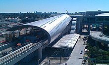 A large, modern elevated train station with two tracks traveling into the structure.