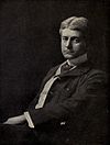 A photograph of a seated Frank Norris, wearing a casual suit and sporting parted hair