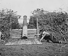 Quaker gun near Centreville, Virginia, in March 1862, after the Confederate withdrawal; a man with a stick is pretending to "fire" it with a linstock Quaker Gun2.jpg