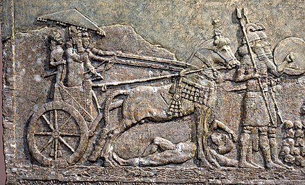 Sargon II in his royal chariot, tramping a dead or dying enemy, part of a war scene from Dur-Sharrukin. Iraq Museum