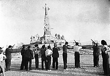 A group of soldiers armed with rifles pointing their guns at a large statue of Jesus Christ.