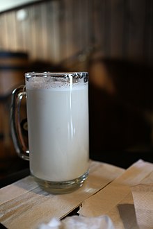 A tall, clear mug filled with a frothy off-white liquid, a London Fog