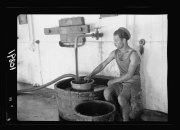 古風なグレープジュースづくりを守り、ぶどうの絞り汁をストレーナーへ通し固形物を取り除く男性（1939年）