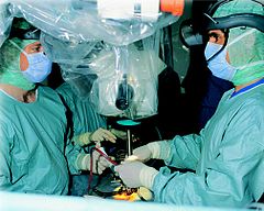 A surgical team in Germany. It has been suggested that surgeons and nurses adopted a cyan-colored gown and operating rooms because it contrasts the color of red blood, thus reducing glare,[28] though the evidence for this claim is limited.