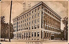 Image of a sepia-tone postcard depicting a five-story brick building constructed in Edwardian-style architecture