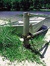 Un bote de remos de metal encadenado a un poste de metal con un lago detrás