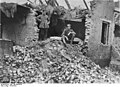 Deux soldats allemands posant devant une maison démolie.