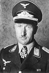 A man wearing a military uniform, peaked cap, e an Iron Cross displayed at the front of his uniform collar