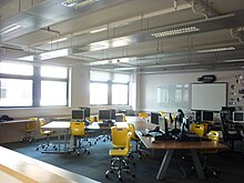 A modern school classroom with natural ventilation by opening windows and exposed thermal mass from a solid concrete floor soffit to help control summertime temperatures Classroom thermal mass.JPG