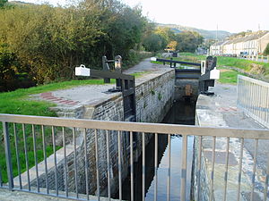 A narrow canal lock with the bottom gate open.