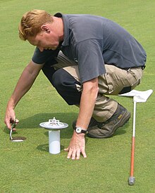 A greenskeeper cuts a hole. Geijsteren 2009 greenkeeper 020.JPG