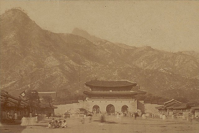 Gwanghwamun in the 1880s, in clear air framed by the mountains and showing surrounding buildings and pedestrians. Photo taken by pioneering Japanese p