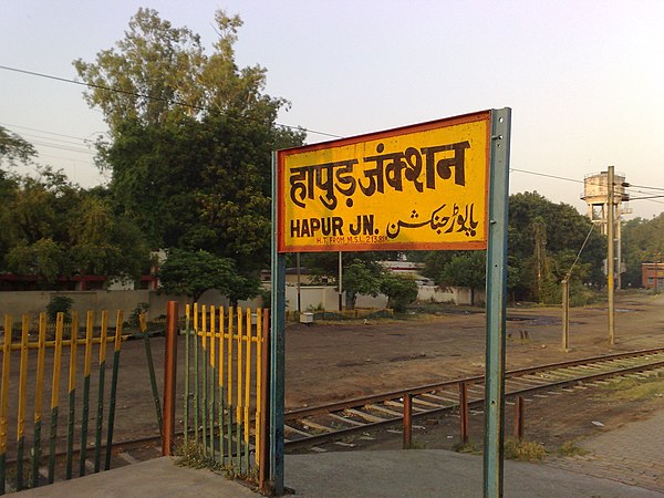 The station board of Hapur Junction railway station in Northern India; Hindustani is an example of triglossia, with a common vernacular and two formal registers.[1] Furthermore, digraphia is present between the two formal registers.[2][3]