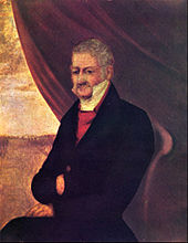 Portrait peint en buste représentant un homme aux cheveux gris au visage fin vêtu d'un manteau noir uni sur un gilet rouge et une chemise blanche à col haut et assis devant un drapé entrouvert laissant apparaître une avenue avec un immeuble au loin