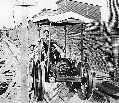 An electric-powered flume cart raises boards to the tops of the drying piles.[13]: 101 