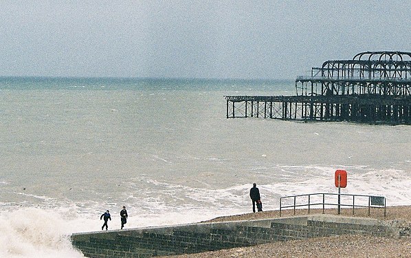 Boys at the seaside racing incoming waves to avoid getting wet