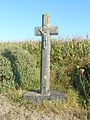 Rosnoën : la croix de Pen-ar-Hoat (Moyen Âge ou XVIe siècle), croix monolithe en schiste portant, en demi-relief, un Christ en croix aux pieds joints[84].