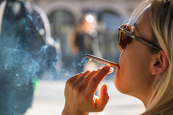 A woman smoking a cigarette, the most common method of tobacco smoking