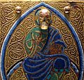 Detail from 13th century Limoges chasse, with a projecting modelled head on a flat background.
