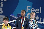 Deutsch: Boxen bei den Olympischen Jugendspielen 2018 Tag 12, 18. Oktober 2018 - Medaillenzeremonie im Leichtgewicht der Mädchen - Gold: Caroline Sara DuBois (Großbritannien), Silber: Porntip Buapa (Thailand), Bronze: Oriana Saputo (Argentinien); Medaillenübergabe durch Habu Gumel (IOC, Nigeria), Geschenkübergabe durch Raymond Silvas (USA, AIBA). English: Boxing at the 2018 Summer Youth Olympics on 18 October 2018 – Girl's Lightweight Medal Ceremony - Gold: Caroline Sara DuBois (Great Britain), Silver: Porntip Buapa (Thailand), Bronze: Oriana Saputo (Argentina); Medal handover by Habu Gumel (IOC, Nigeria), Gift presented by Raymond Silvas (USA, AIBA). Español: Boxeo en los Juegos Olímpicos Juveniles de Verano de 2018 en 18 de octubre de 2018 - Ceremonia de la Medalla de peso ligero para niñas - Oro: Caroline Sara DuBois (Gran Bretaña), Plata: Porntip Buapa (Thailand), Bronce: Oriana Saputo (Argentina); Entrega de medallas por Habu Gumel (COI, Nigeria), Regalo presentado por Raymond Silvas (EE. UU., AIBA).