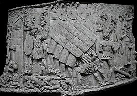 a monochrome photograph of an ancient carving showing Roman soldiers in a testudo or tortoise formation